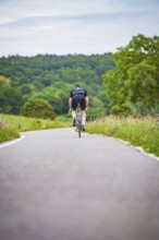 A cyclist rides on a remote road through nature, with trees and grass, triathlon, Calw, Germany