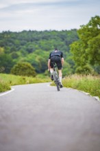 Cyclist climbing a road in hilly countryside surrounded by greenery, triathlon, Calw, Germany