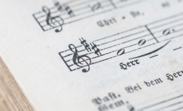 Close-up of a sheet music with musical symbols and text in black and white, historical, old,