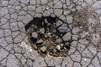 Pothole, asphalt surface, floor, with many small cracks, roadway, parking lot