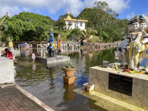 Shore of Sacred Lake Ganga Talao in crater of extinct volcano with blue sculpture of deity Shiva