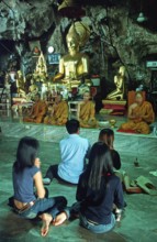Buddha statue, monks and believers praying, Wat Tam Sua monastery near Krabi, Thailand, December