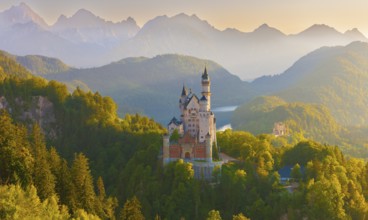 Neuschwanstein Castle in the midst of a fairytale alpine panorama during sunrise surrounded by