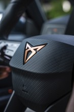 Detailed view of a steering wheel with brand emblem and textured surface, Cupra electric car, e-car