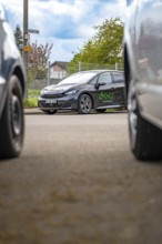 A modern car is parked between other vehicles on an urban road, Cupra electric car, e-car sharing,