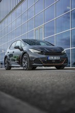 An elegant car depicted on asphalt in front of a glass façade, electric car Cupra, e-car sharing,