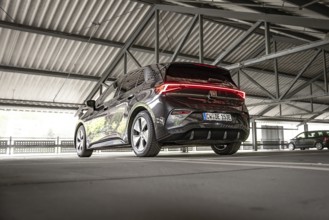 Modern black car in an urban parking garage from the rear view, Cupra electric car, e-car sharing,