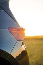Close-up of a car light at sunset with golden evening mood in the background, electric car Cupra,