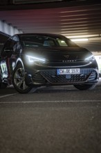 Black car with dramatically glowing LEDs in a dark garage setting, Cupra electric car, e-car