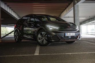 Black car with glowing LED headlights parked in dark parking garage, Cupra electric car, e-car