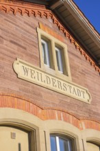 Brick building with Weilderstadt lettering under blue sky, Weil der Stadt railway station, Germany