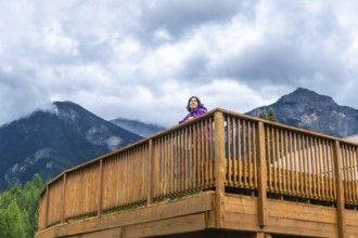 Tourist is standing on a wooden viewpoint, embracing the majestic scenery of mount robson in the