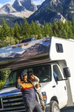 Father and son giving thumbs up in front of their rv, enjoying breathtaking views of mount robson
