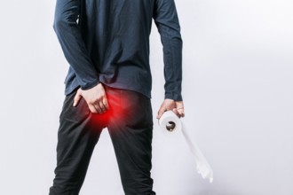 Man with diarrhea problem, man with toilet paper in hand touching his buttock, man with hemorrhoid