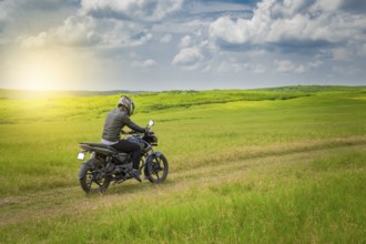 Biker man on a country road, young man on his motorcycle traveling through the countryside with