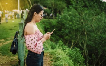 Latin woman checking her cell phone, pretty girl in glasses checking her cell phone