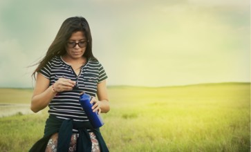 Girl in the field drinking water. Concept of woman in the field drinking water