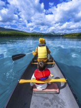 Father and son paddling a canoe on maligne lake's turquoise waters, surrounded by mountains and