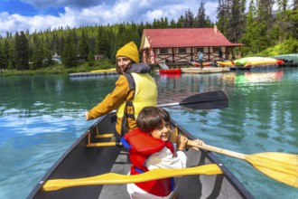 Mother and son are paddling a canoe on the beautiful turquoise maligne lake in jasper national