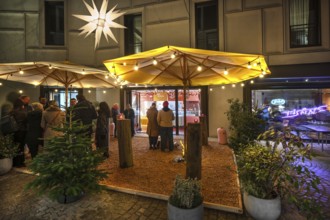 Visitors standing outside a café during the evening Advent season, Nuremberg, Middle Franconia,