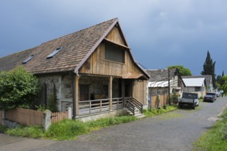 Rural scenery with wooden houses and parked cars under a cloudy sky, Schwabenstraße, village