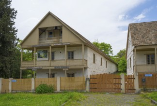 Traditional house with wooden balcony and fence in a rural setting with cloudy skies, village