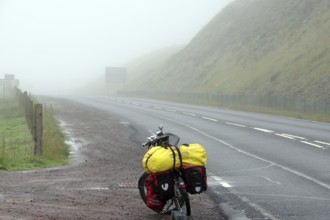 Bicycle with luggage on a foggy and deserted country road, cycle tourism, adventure, Shetlands,
