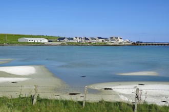 Small village on a peaceful coast with blue water and clear skies, Pierowall, Orkney Islands,