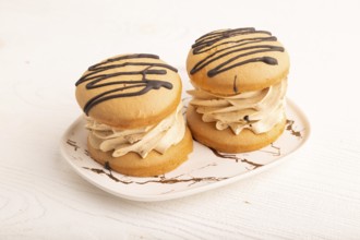 Caramel Cream Cakes on white wooden background, side view, close up