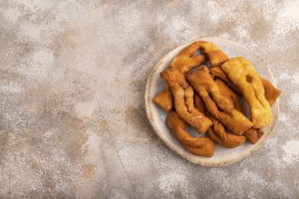 Crunchy biscuit Brushwood cookies sprinkled with powdered sugar on brown concrete background, top
