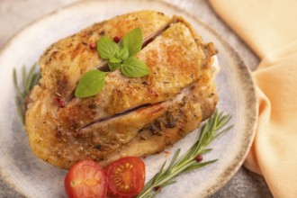 Fried Turkey Thigh with spices and rosemary on plate on brown concrete background and orange linen