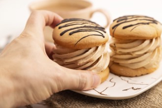 Caramel Cream Cakes with hand on white wooden background and linen textile, cup of coffee, side