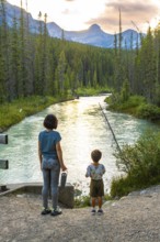 Mother and her son are enjoying the breathtaking view of a pristine river flowing through a lush