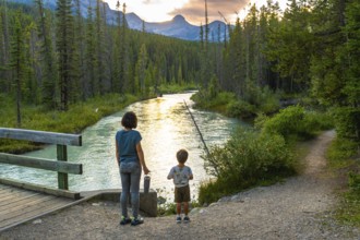 Mother and her son are enjoying a breathtaking sunset view over a pristine river flowing through