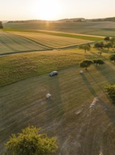 Car in a vast, sunny field landscape during sunset, deer e-car sharing, Cupra electric car,