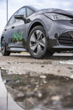 Car with reflection in a wet puddle on a street, Deer E-Car Sharing, Cupra electric car, Germany