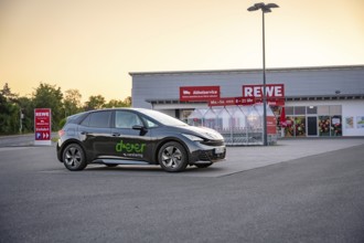 Car parked in a parking lot in front of a supermarket in the evening light, Deer e-car sharing,