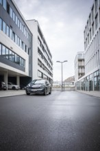 A car is parked on an empty street between modern buildings, Deer E-Car Sharing, Cupra electric