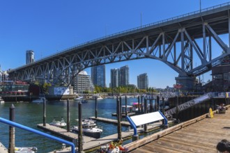 Granville street bridge dominating the skyline over false creek with boats moored at the marina and