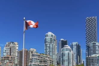 Canadian flag waving proudly in the foreground with the modern skyline of vancouver, british