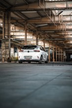 White car parked in empty industrial building, urban industrial look, deer e-car sharing,