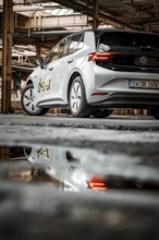 The vehicle is reflected in a puddle on the floor of an abandoned factory, Deer E-Car Sharing,