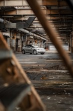 A car is parked in an abandoned factory building that exudes a rusty, mysterious charm, Deer E-Car
