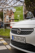 White Opel front in the foreground with car sharing advertising in the background, Deer E-Car