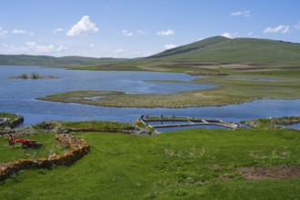 Beautiful lake with green shores and rolling hills under blue skies, Lake Saghamo,