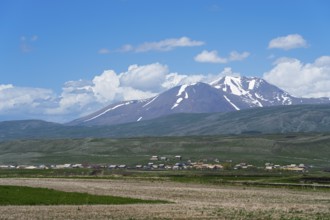 View of snow-capped mountains behind vast fields and a village, landscape near Satche, Mount Didi