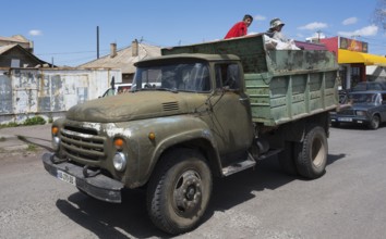 Old truck with men on a village road under blue sky, ZIL-130 truck, Samtskhe—Javakheti region,