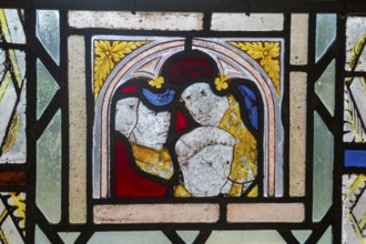 Close-up of medieval style stained glass showing faces of people, Ufford church, Suffolk, England,
