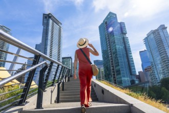 Tourist wearing a straw hat walking up stairs in vancouver, british columbia, canada with modern