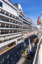 Large cruise ship docking in vancouver, british columbia, with lifeboats hanging from the side and